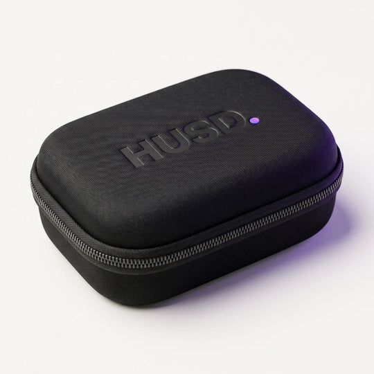 The closed HUSD travel case, a matte black hard shell with a full-perimeter zip