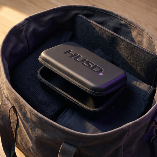 The case packed on top of folded clothing inside a canvas weekend bag