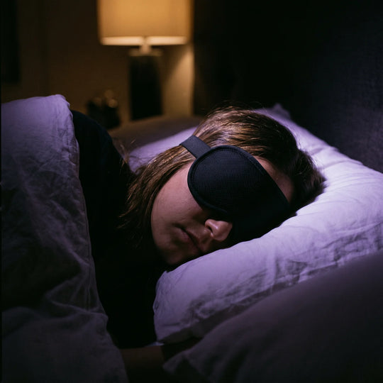 A side sleeper wearing the mask, the flat strap lying smooth against the pillow