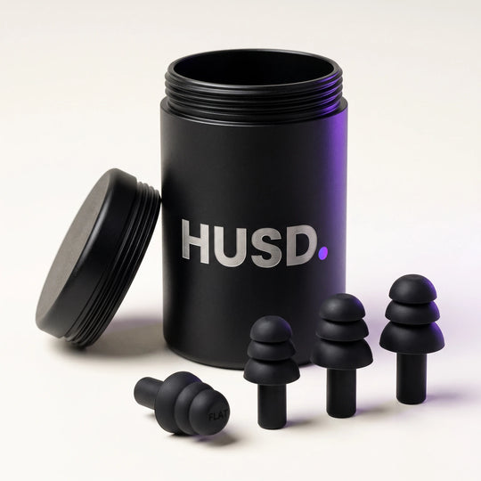 The aluminium HUSD case with its lid off and three pairs of silicone earplugs in front of it
