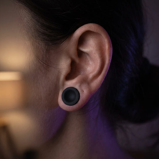 An earplug seated in an ear, its flat face sitting flush so nothing protrudes