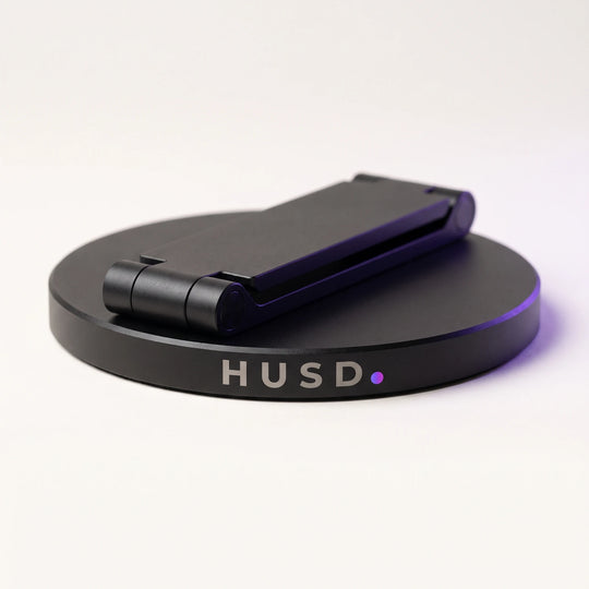 The stand folded flat against its base, the etched HUSD mark on the rim