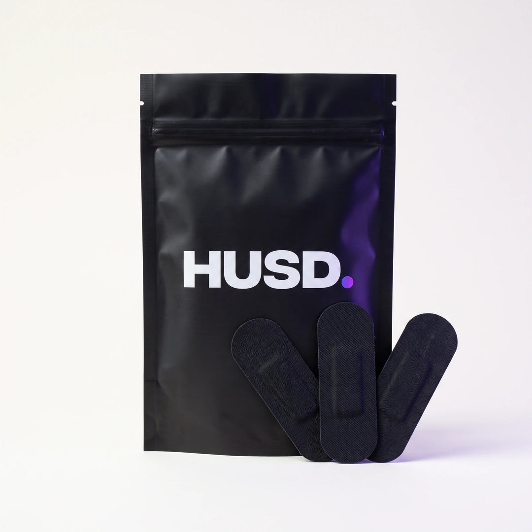 A HUSD pouch standing upright with three matte black nasal strips fanned out in front of it