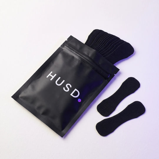 The resealable pouch open, a stack of nasal strips sliding out of it